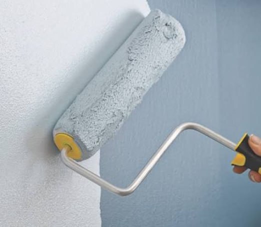 Paint roller applying paint to wall